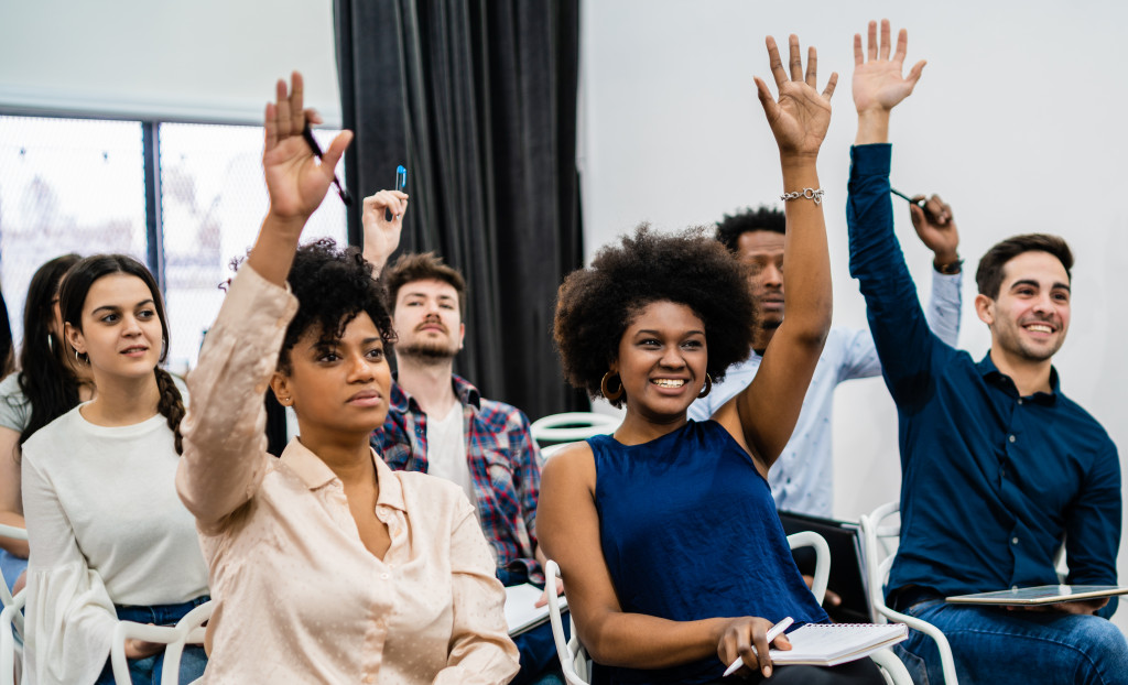 Diverse group of employees raise their hands at a workshop to ask questions
