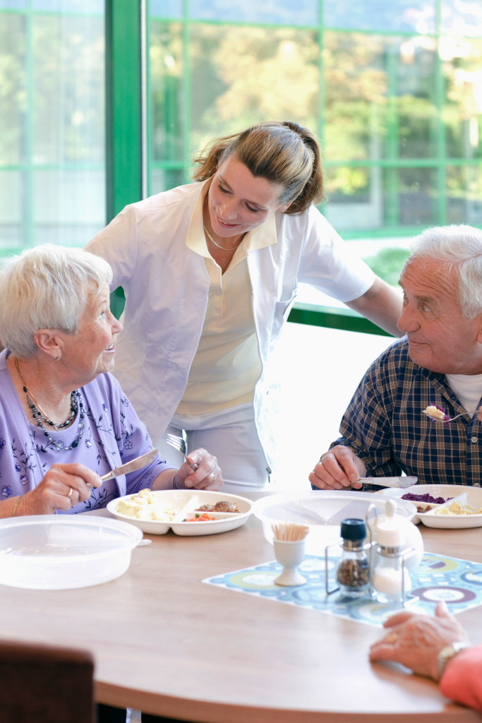 a woman talks to elderly people while eating