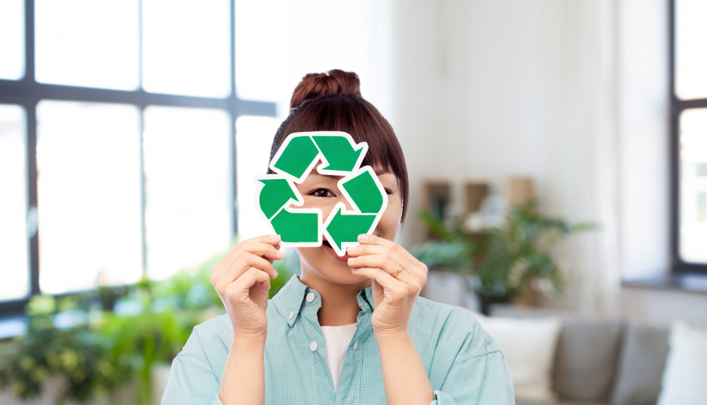 Young employee holding a green recycling symbol while in an office.